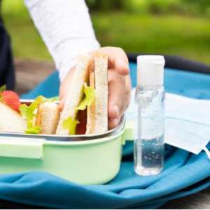 lunchbox-with-sandwiches-strawberries-sanitizer-face-mask-on-blue-picture-id1270994883